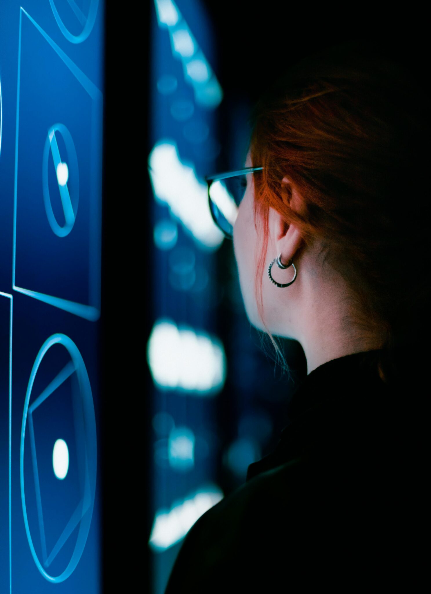 A woman with eyeglasses interacts with an illuminated digital screen, showcasing modern technology.